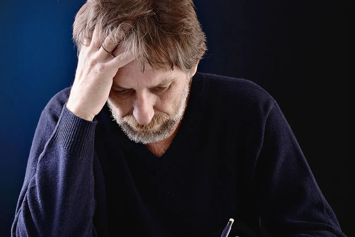 A middle-aged man reviewing financial paperwork with a calculator, representing the financial-runway planning a career change at 50 requires