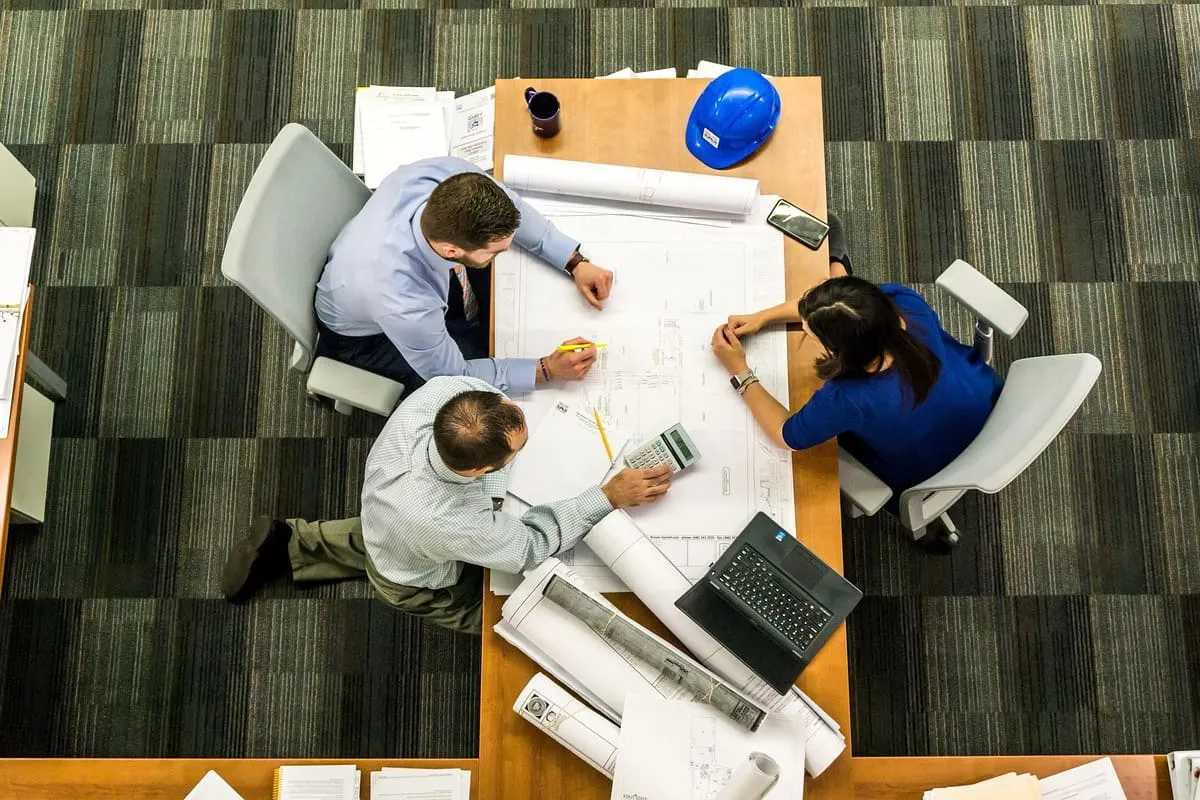 A small team reviewing plans together around a table, representing the cross-functional collaboration skills that transfer across industries